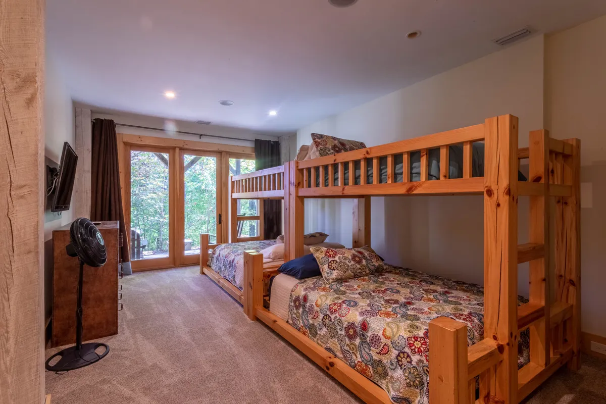 A bright, playful bunk room with built-in bunk beds, colorful bedding, and large windows that let in natural light. The space feels fun and inviting, perfect for children or young guests and designed for sleepover excitement and bonding.