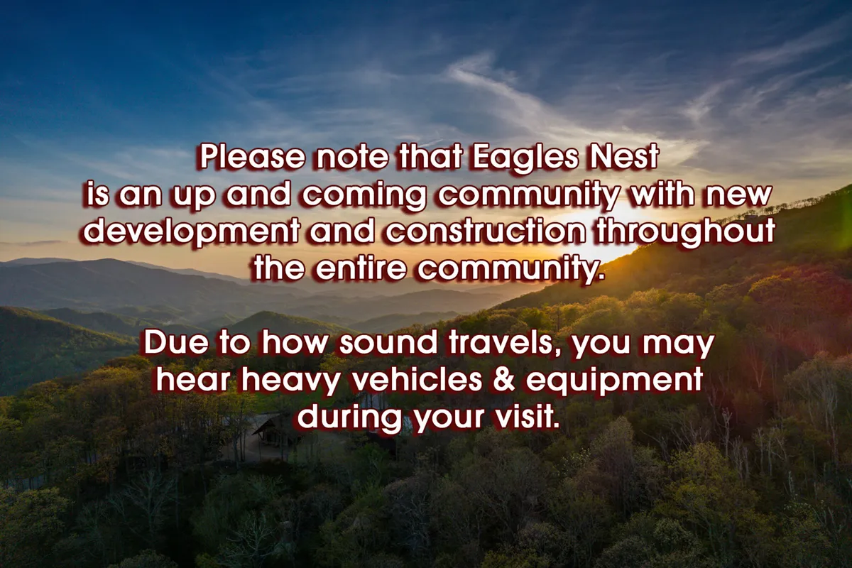 A breathtaking view of a mountain range at sunset, framed by lush greenery in the foreground. The vibrant sky and expansive landscape evoke a sense of adventure and the natural beauty surrounding Eagles Nest.